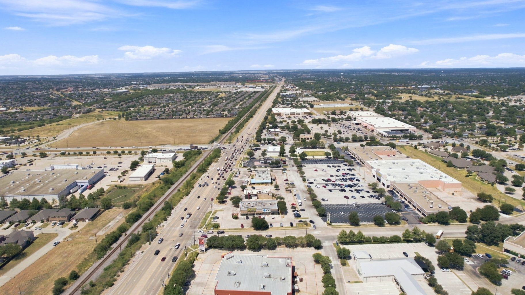 Aerial view of a commercial development, major roadway, parking areas, surrounding properties, and location context
