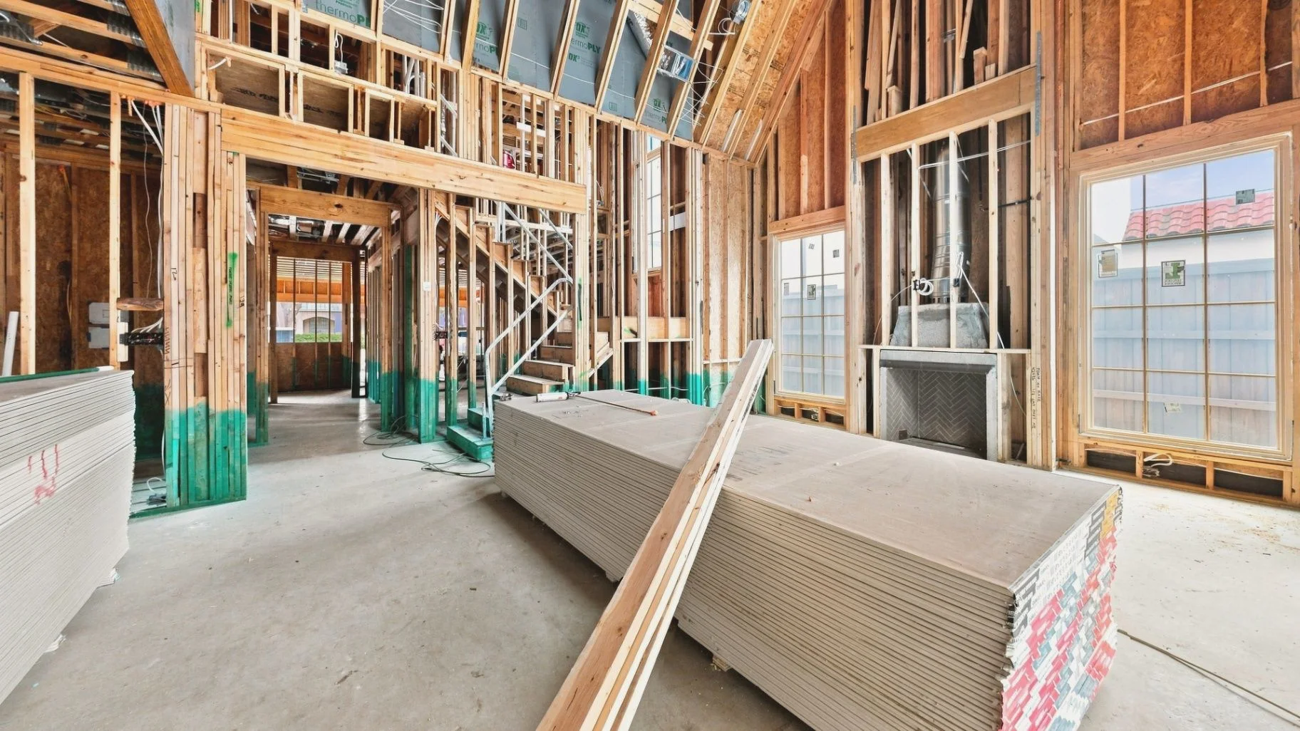 Ground-level construction interior with drywall materials, staircase, and unfinished building conditions
