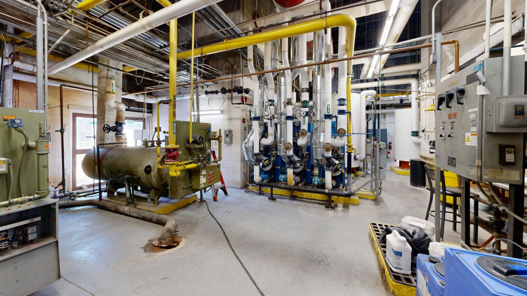 Mechanical systems room with multiple pieces of equipment, piping, controls, and surrounding space